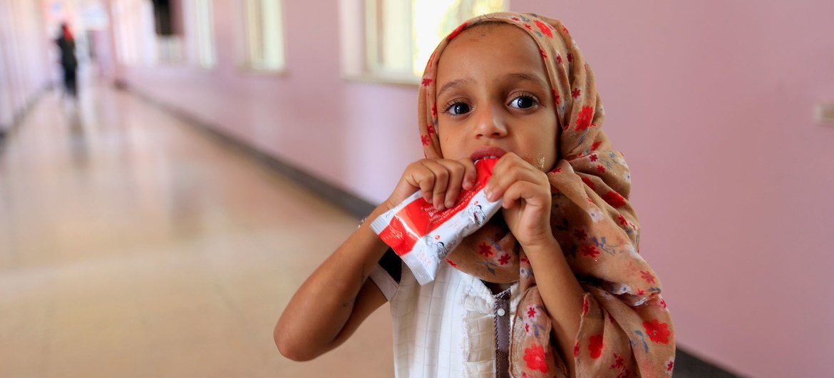 یک دختر کوچک در حالی که در بیمارستانی در صعنا، یمن به دلیل سوءتغذیه تحت درمان قرار می گیرد، یک خمیر بادام زمینی می خورد.