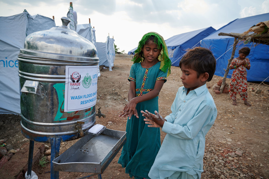 کودکان آواره دست های خود را بیرون از یک توالت عمومی در اردوگاهی در استان سند پاکستان می شویند.